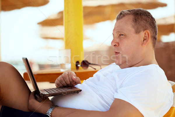 Man relaxing with a laptop at beach resort Stock photo © d13