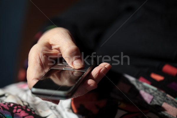 Old woman is going to dial a number on her cell phone Stock photo © d13