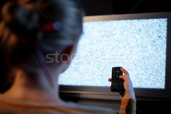 Woman with remote control in front of TV set Stock photo © d13