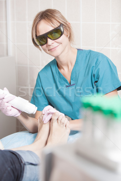 Smiling cosmetician working with laser to treat feet Stock photo © d13
