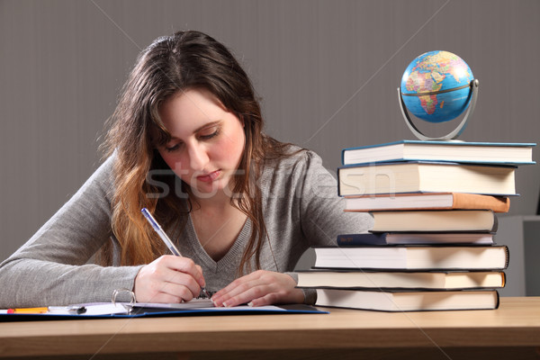 Young student girl writing with books around her Stock photo © darrinhenry