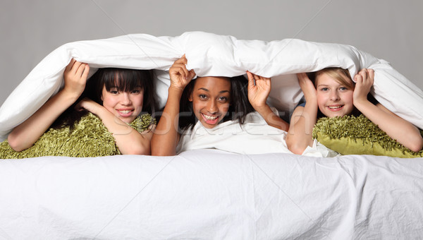 Sleepover party fun teenage girls laughing in bed Stock photo © darrinhenry