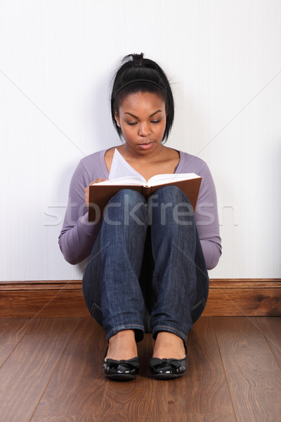 Beautiful woman sitting on floor reading a book Stock photo © darrinhenry