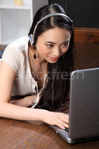 Asian girl with headphones using skype on laptop Stock photo © darrinhenry