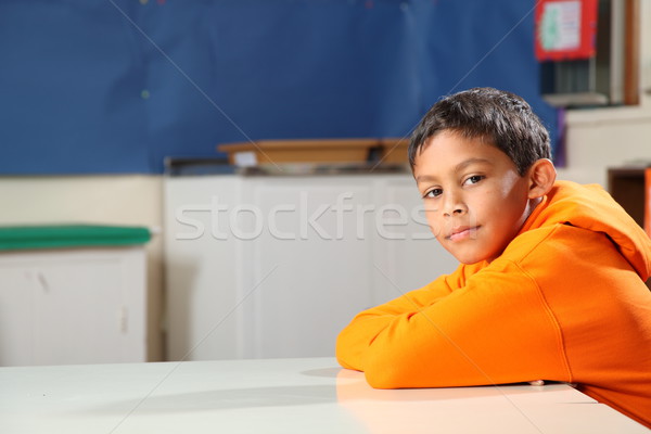 Stock photo: Schoolboy 10 arms folded deep in thought at classroom desk