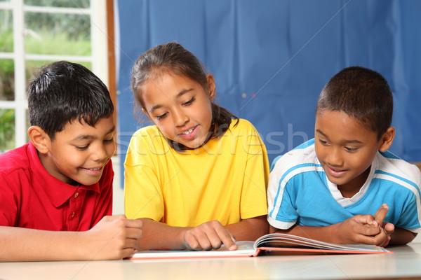 Learning together three primary school kids reading book in class Stock photo © darrinhenry