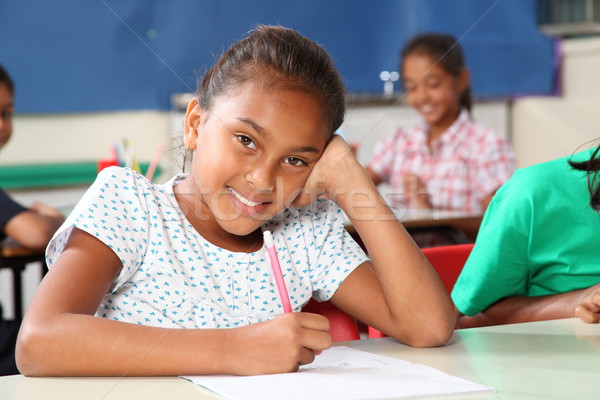 Happy school girl with beautiful smile working away in classroom Stock photo © darrinhenry