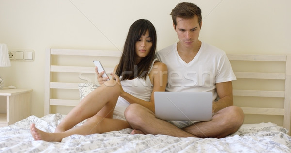 Young serious couple sitting together in bed Stock photo © dash