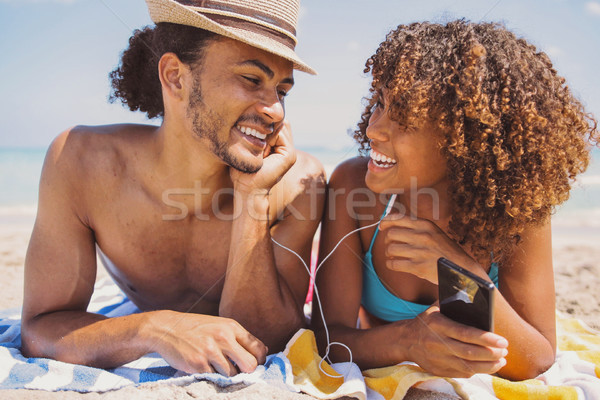 Couple on beach listening to music and smiling Stock photo © dash
