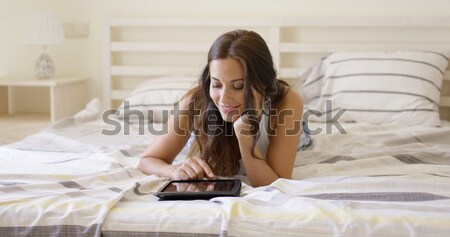 Young woman laying down in bed using laptop Stock photo © dash