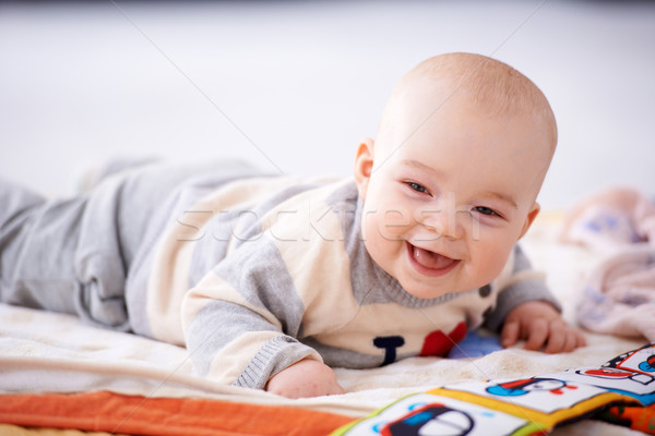 Happy gurgling baby lying on his bed Stock photo © dash