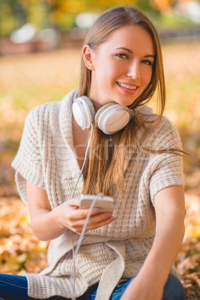 Vonzó fiatal nő zenét hallgat ül kint tart Stock fotó © dash
