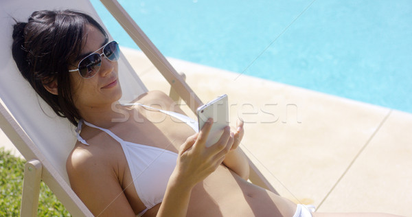 Woman in white bikini checks her cell phone Stock photo © dash
