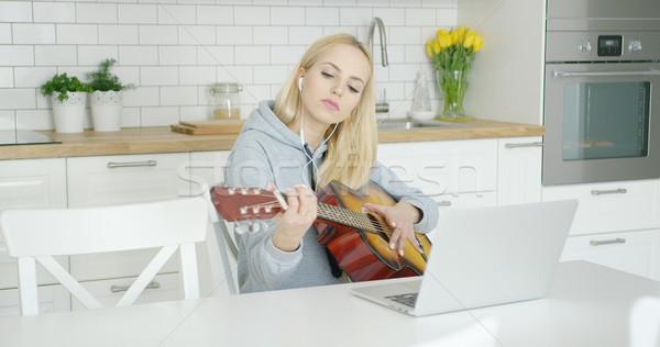 Stock photo: Female guitarist practicing at home