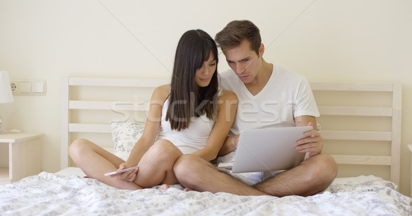 Couple sitting together in bed using computer Stock photo © dash
