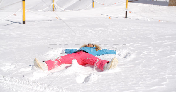 Stock photo: Young woman making a angel in white snow