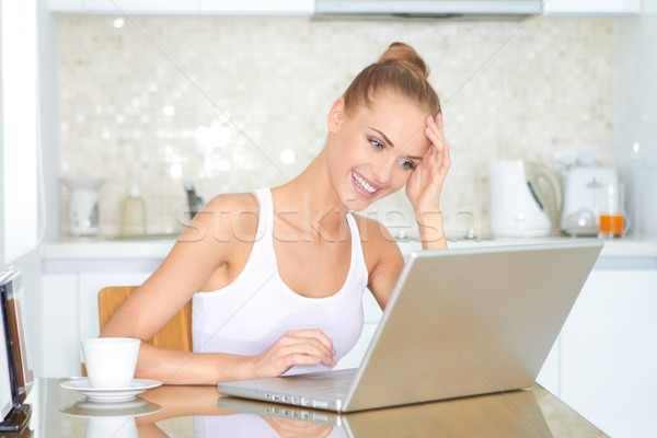 Young woman working on a laptop in the kitchen Stock photo © dash