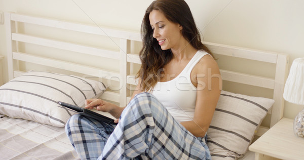 Young woman sitting on her bed using a tablet Stock photo © dash