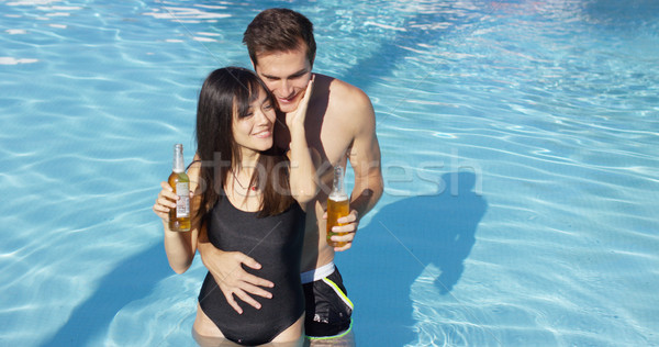 Stock photo: Couple in swimming pool hold frothy drinks