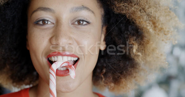 Fun young woman biting Christmas candy cane Stock photo © dash