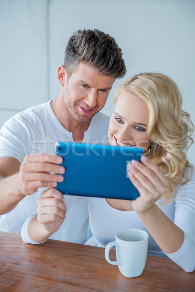 Couple smiling as they read a tablet computer Stock photo © dash