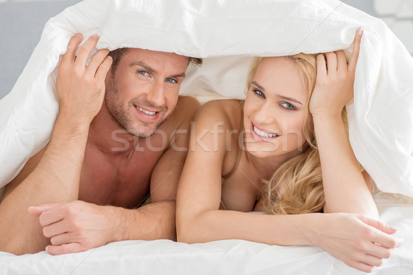 Young couple peeking out from under the bedclothes Stock photo © dash