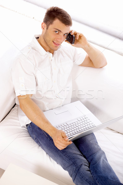 Young Salesman on Couch Using Phone and Laptop Stock photo © dash