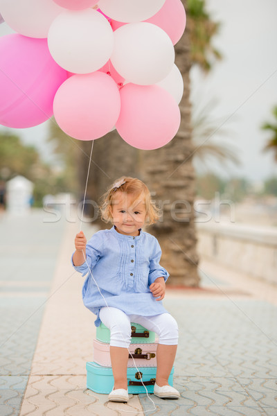 Happy little girl holding a bunch of balloons Stock photo © dash