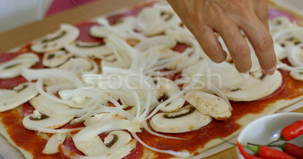 Woman placing onion on a homemade pizza Stock photo © dash