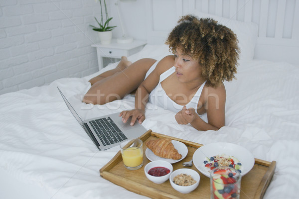 Stock photo: Content woman using laptop while having meal