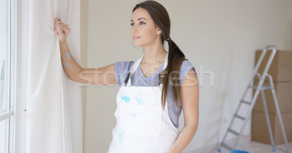 Stock photo: Young woman standing gazing out of a window