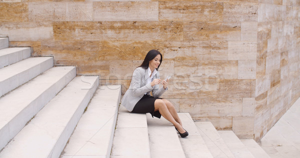 Pretty business woman sitting on steps using phone Stock photo © dash