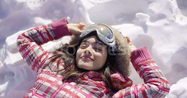 Young woman lying on snow with ski goggles Stock photo © dash