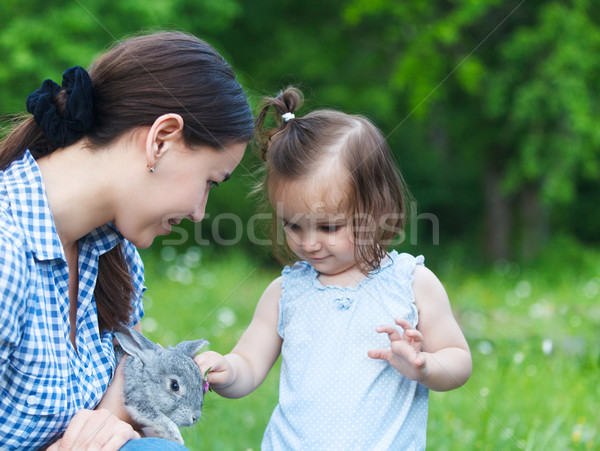 Cute little girl and her mother hugging little grey rabbit Stock photo © dashapetrenko