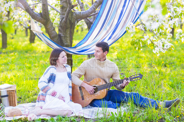 Pregnant couple in blooming garden at the picnic Stock photo © dashapetrenko