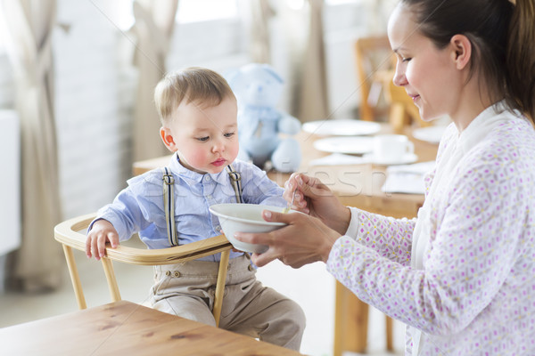 Stock photo: Beautiful young woman feeds her baby son 