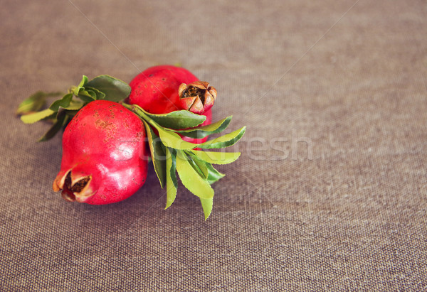 Stock photo: Two pomegranate fruits with leaves on textile background 
