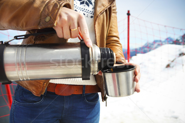 Stock photo: Young woman holding thermos on mountain top in winter