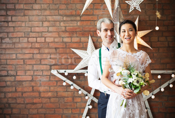 Stock photo: Cheerful married couple standing near the brick wall 