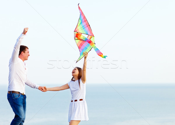 Happy couple in love with flying a kite on the beach Stock photo © dashapetrenko