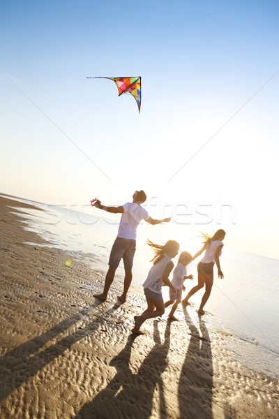 Happy young family with flying a kite on the beach Stock photo © dashapetrenko