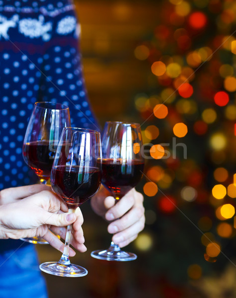 Clinking glasses of red wine in hands on Christmas lights backgr Stock photo © dashapetrenko