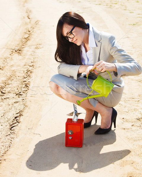 Stock photo: Businesswoman watering a money in safe 