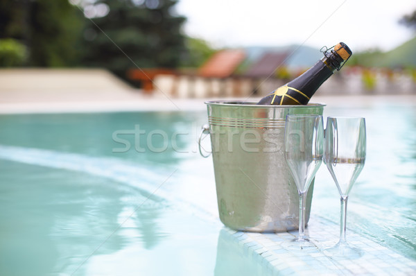 Ice bucket champagne bottle and two glasses near pool Stock photo © dashapetrenko