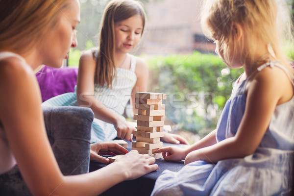 Happy mother with two children playing the wooden blocks tower Stock photo © dashapetrenko