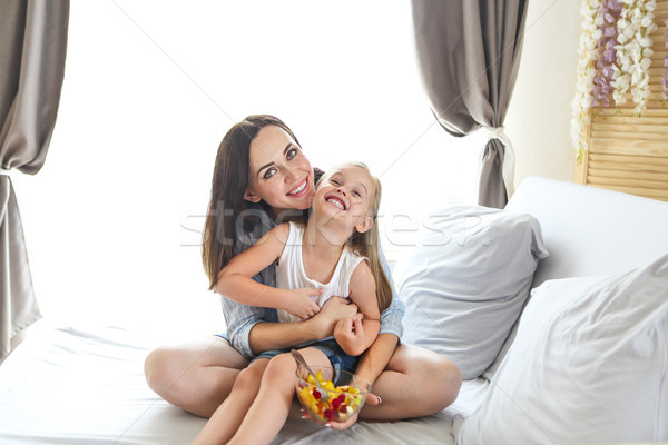 Mother and daughter sitting with arm around on bed at home Stock photo © dashapetrenko