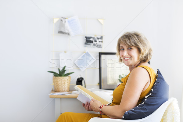 Stock photo: Mature woman reading book in the living room