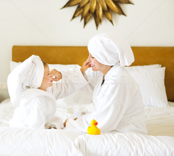Happy mother and daughter in bathrobes with cream mask Stock photo © dashapetrenko