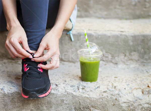 Green detox smoothie cup and woman lacing running shoes before w Stock photo © dashapetrenko