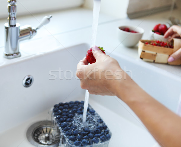 Cropped image of woman washing blueberry, strawberry and red cur Stock photo © dashapetrenko